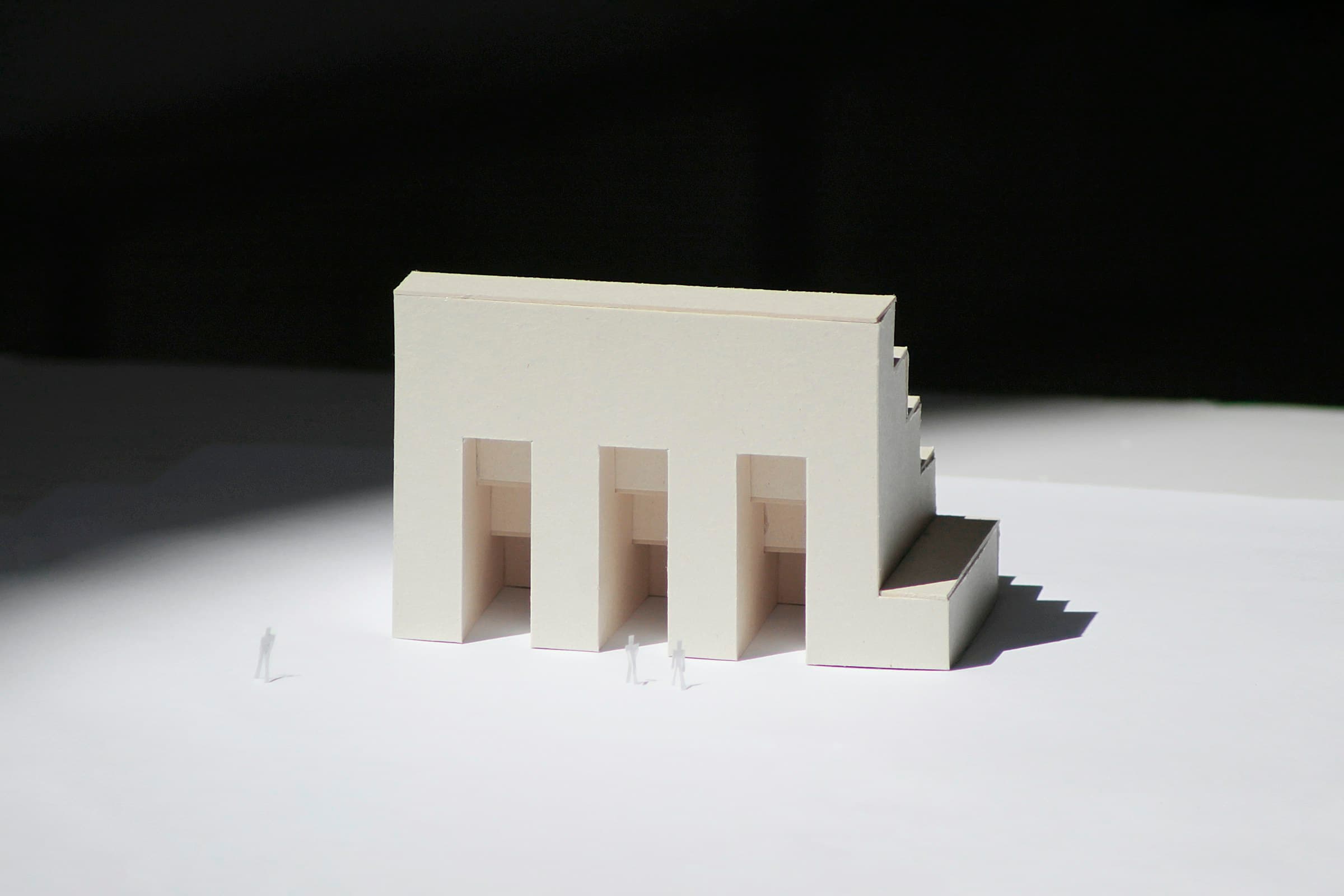 A white card architectural model with three doorways.